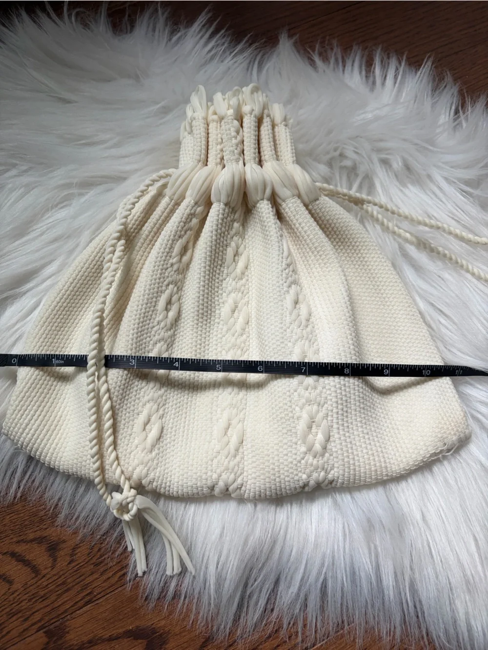 Cream cable knit drawstring bag with braided rope details